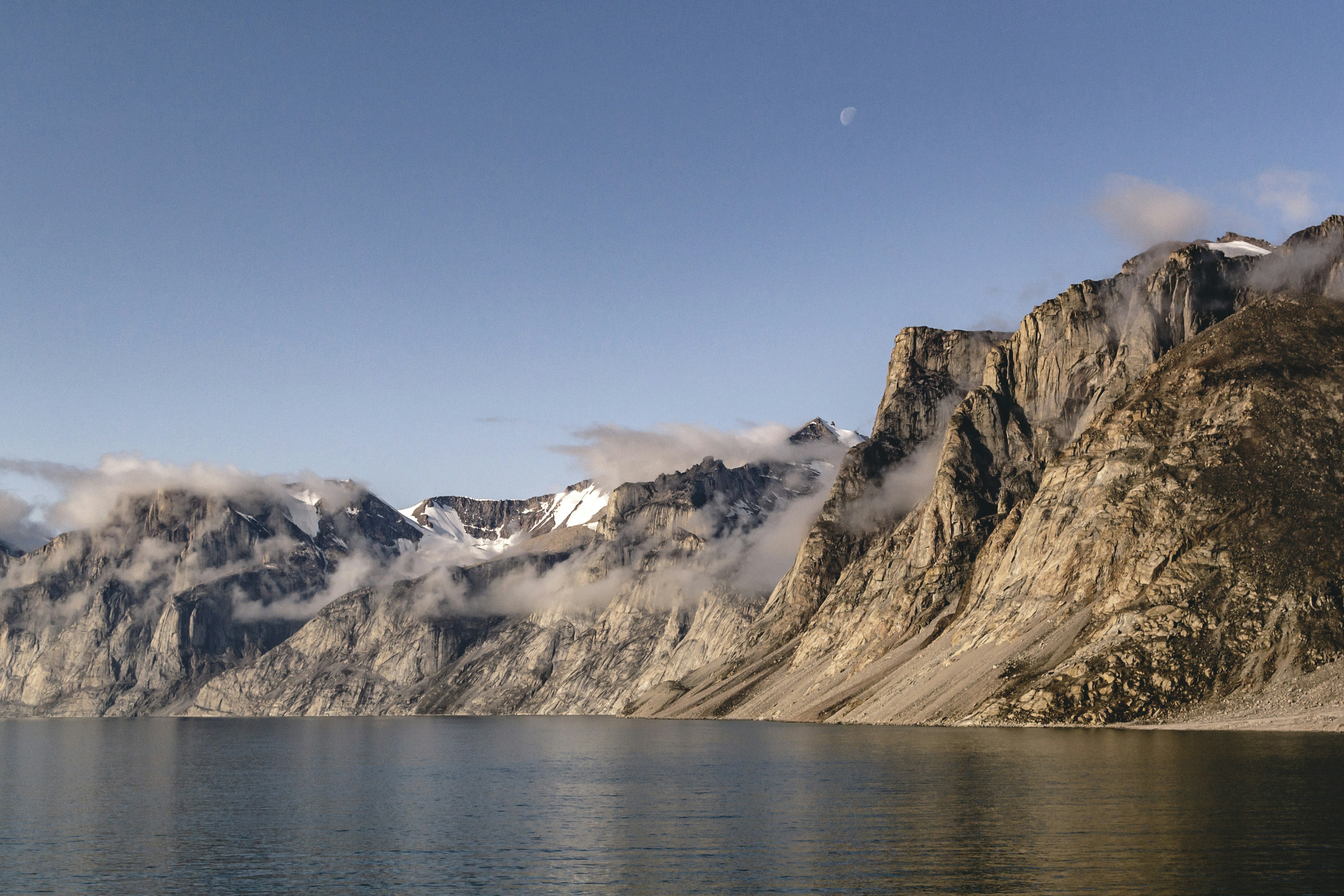 brown and white mountains near body of water during daytime, Moonrise over the rocky mountains in the Canadian Arctic