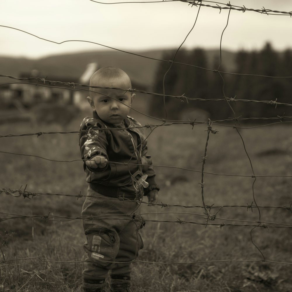 boy in brown and black camouflage jacket standing on green grass field during daytime