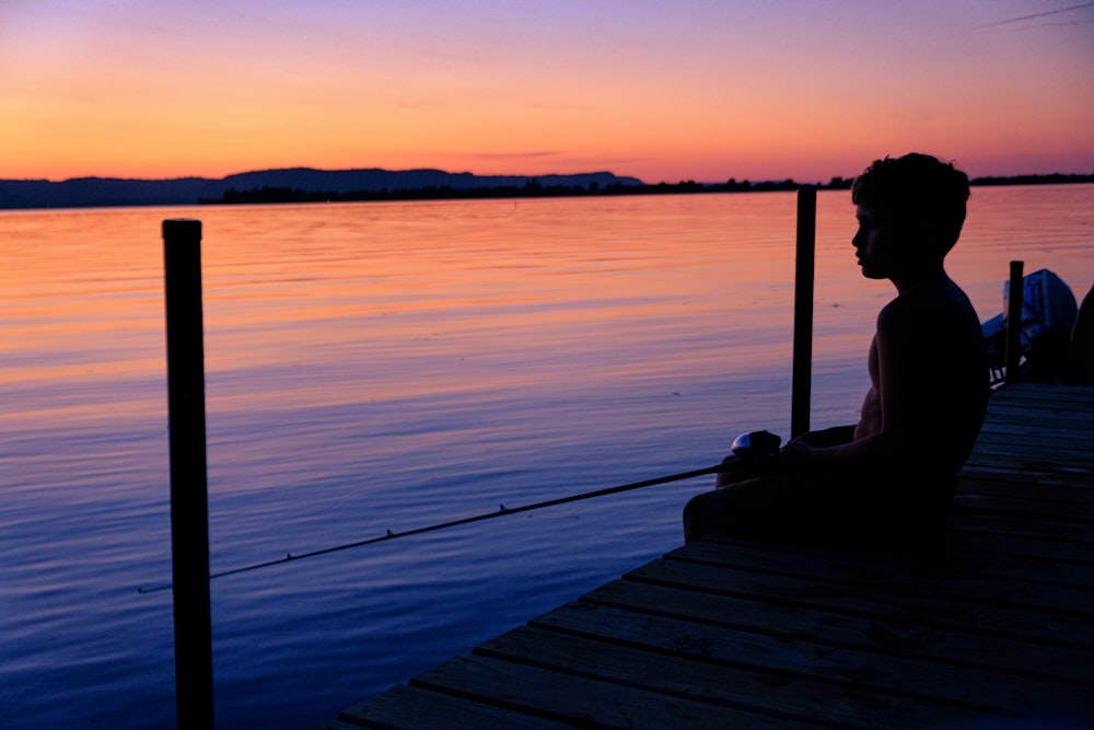 woman sitting on dock during sunset