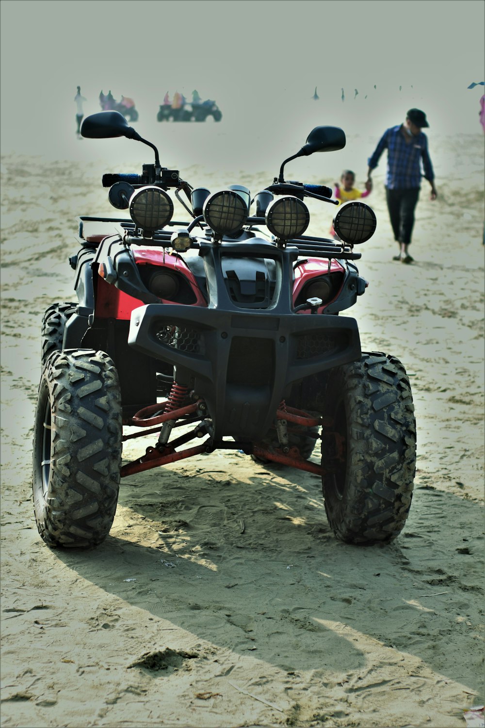 Schwarzes und rotes ATV auf weißem Sand tagsüber