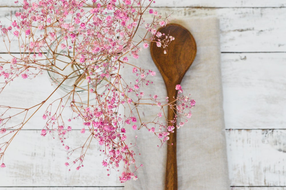 brown wooden spoon on white and pink floral textile