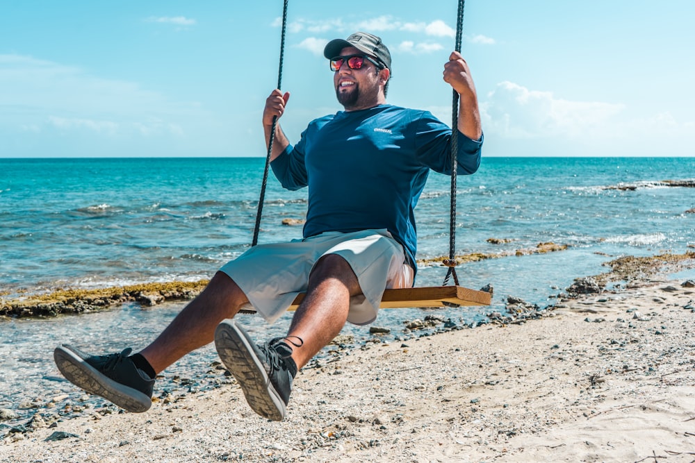 man in red crew neck t-shirt sitting on swing during daytime