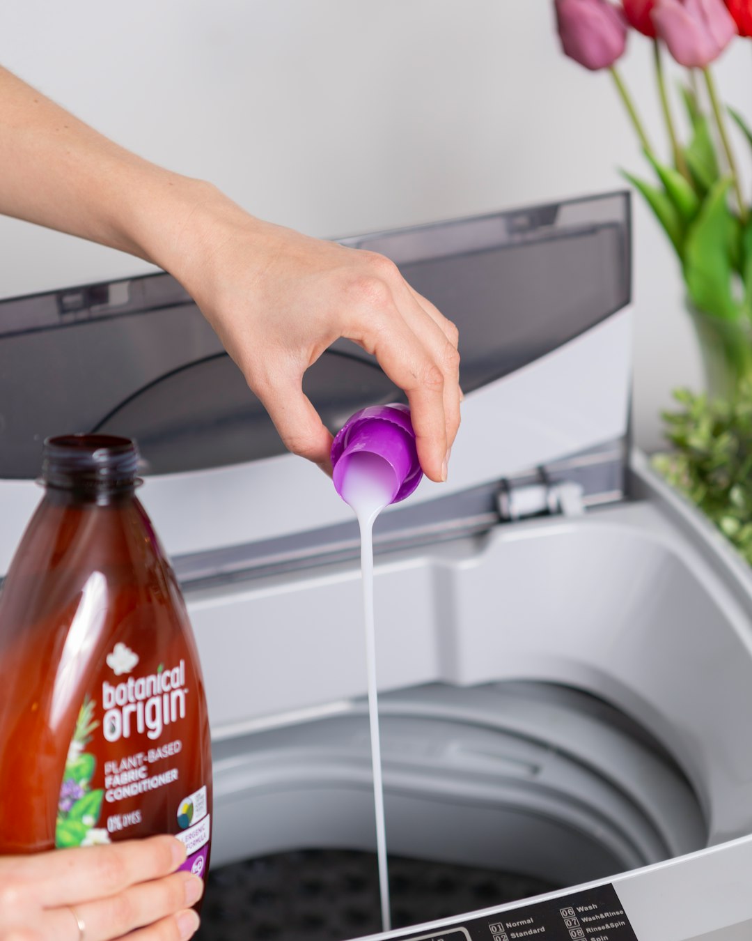  person holding purple plastic bottle washing machine