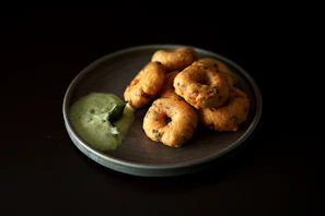 Freshly made vada with a crispy exterior, placed on a banana leaf with chutney.