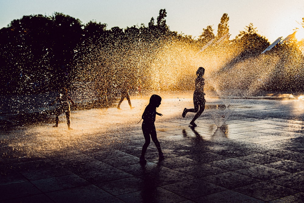 silhouette of girl playing on water fountain during night time