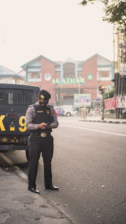 man in black jacket and black pants standing on road during daytime
