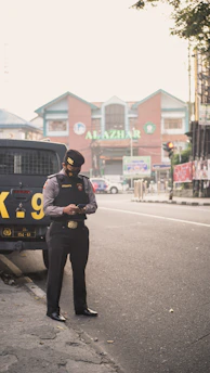 man in black jacket and black pants standing on road during daytime