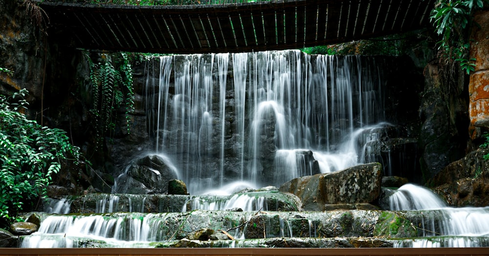 water falls under bridge during daytime