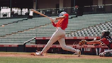 woman in red jersey shirt and white shorts holding baseball bat