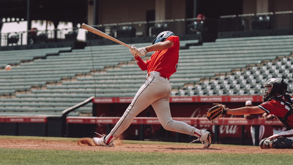 Mujer con camisa de punto rojo y pantalones cortos blancos sosteniendo un bate de béisbol