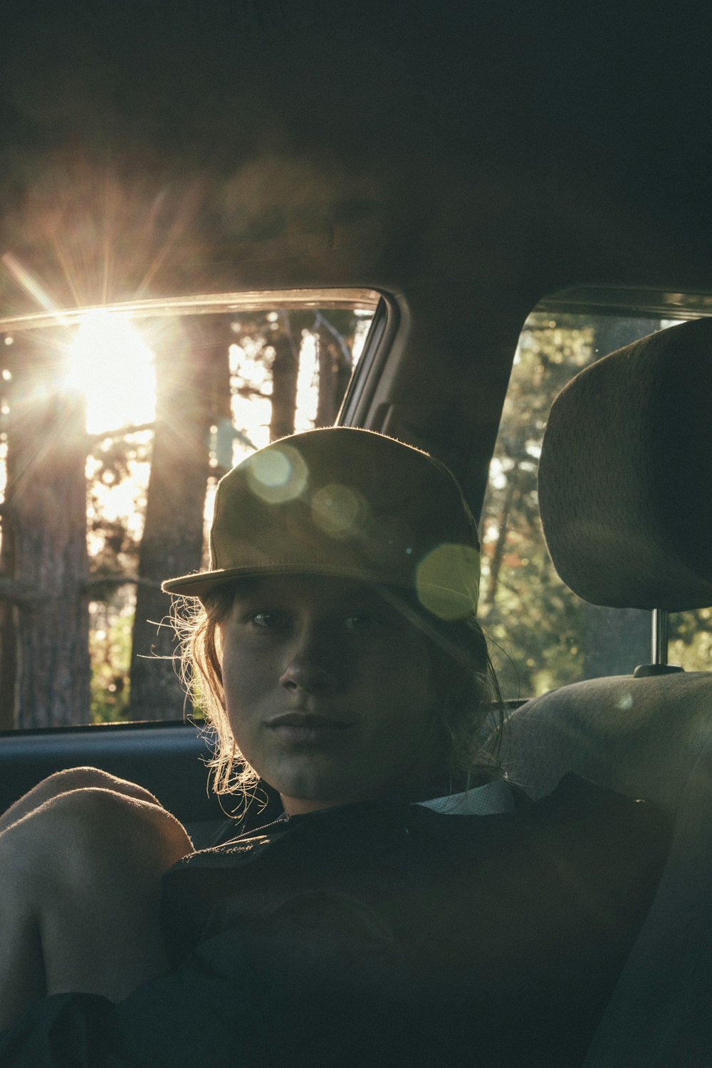 woman in black shirt wearing black hat sitting inside car during daytime