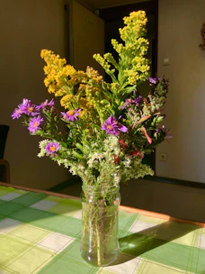 A close-up of textured ceramic vases in cheerful hues, holding fresh wildflowers on a sunny windowsill.