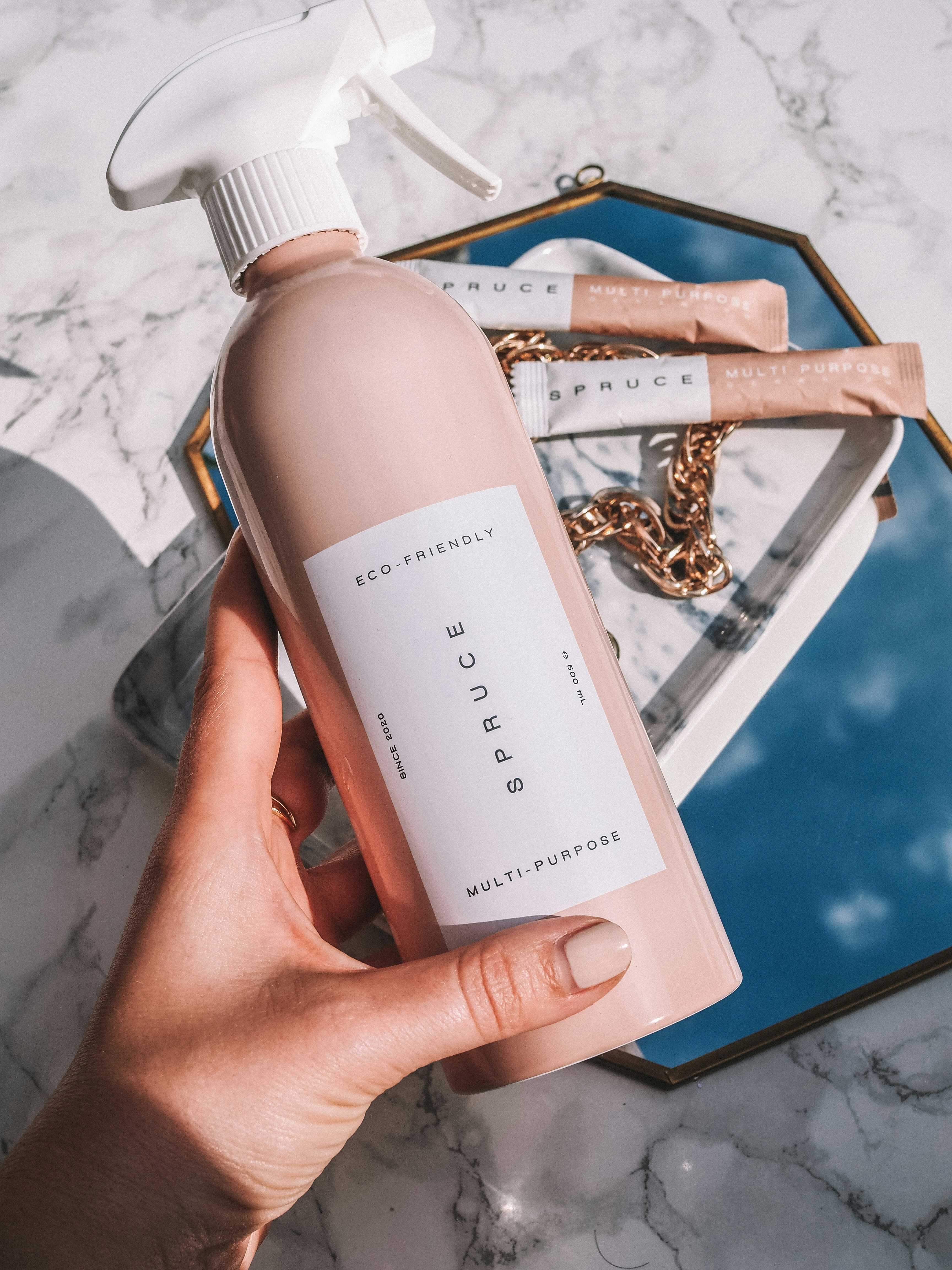 Elegant glass bottle of ARZERA fabric protector spray on marble surface with luxury curtain fabric