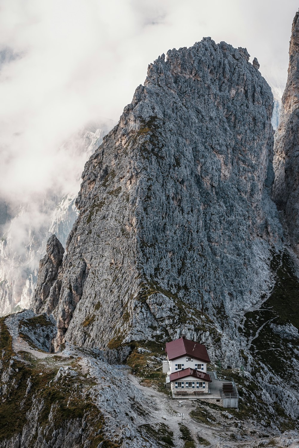 red and white house on rocky mountain under cloudy sky during daytime