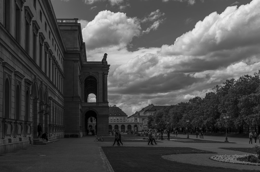 grayscale photo of people walking on street near building