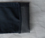 Close-up of a pair of dark indigo jeans with detailed stitching on a wooden table.