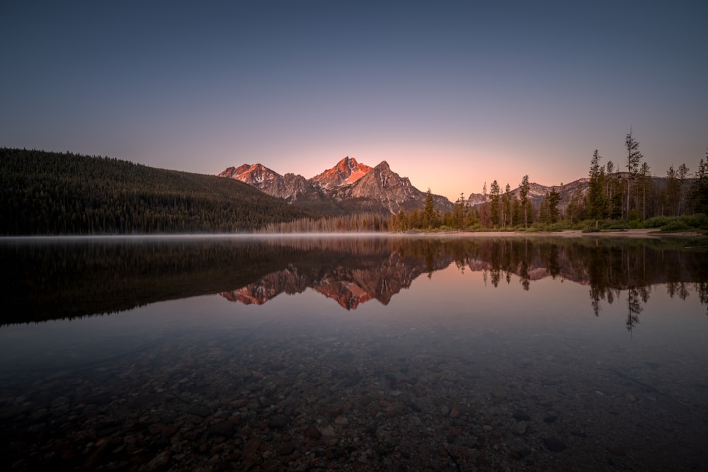 lake near mountain under blue sky during daytime