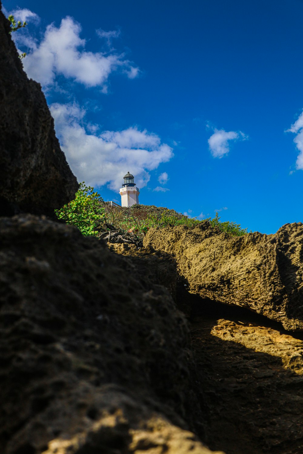 white and brown lighthouse on brown rocky mountain under blue sky during daytime