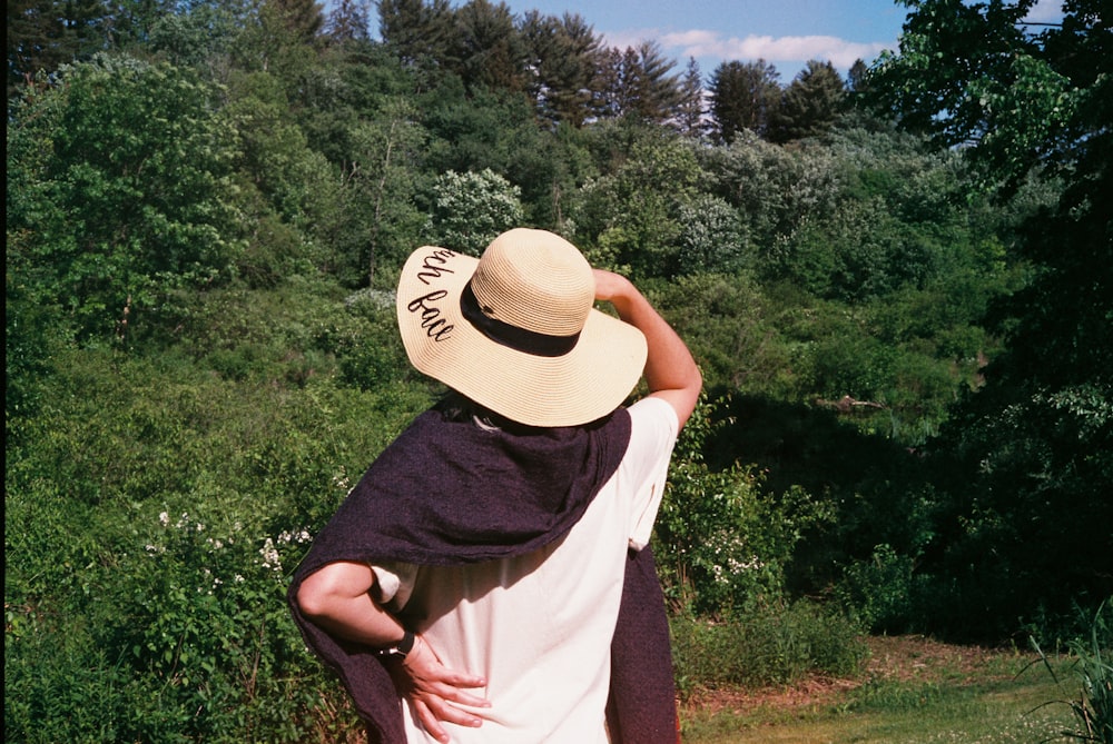 woman in white shirt and brown hat standing on green grass field during daytime