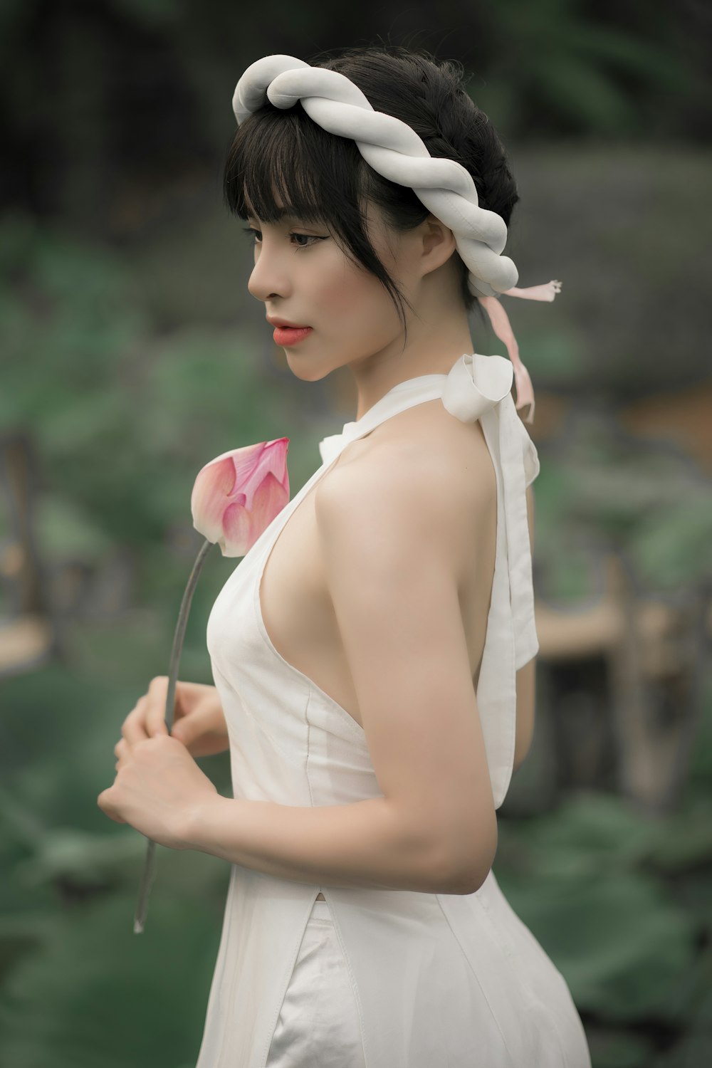 woman in white tank top holding pink flower
