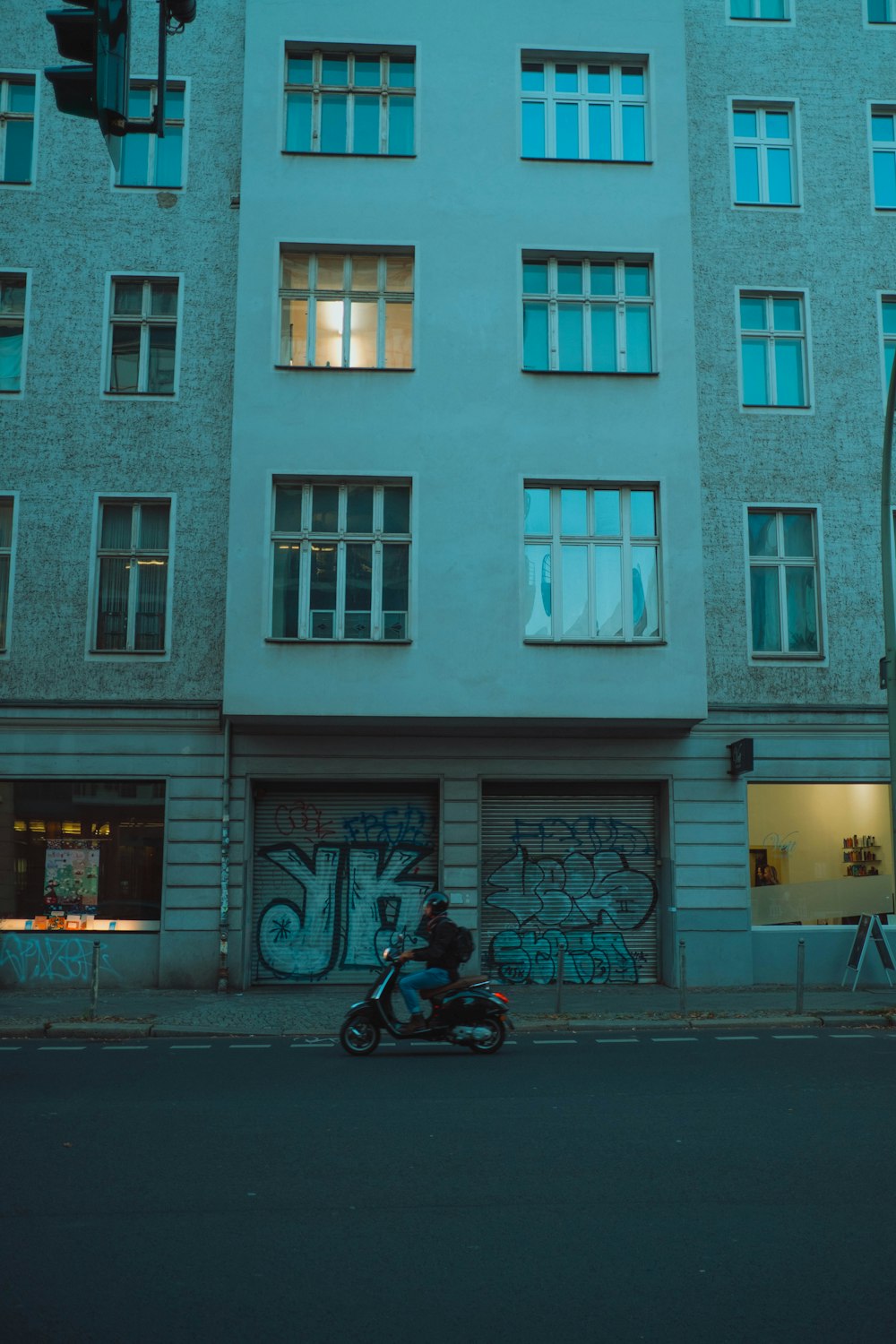 man in black jacket riding motorcycle near white concrete building during daytime