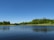 A serene lake surrounded by trees under a clear blue sky.