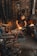 A person is working in a blacksmith's workshop, hammering a metal piece on an anvil with sparks flying. The workshop is filled with tools, equipment, and a lit furnace in the background. The walls are made of stone and the atmosphere is gritty and industrious.