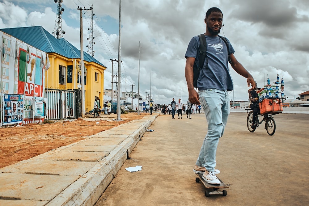 man in blue denim jeans and black t-shirt walking on sidewalk during daytime