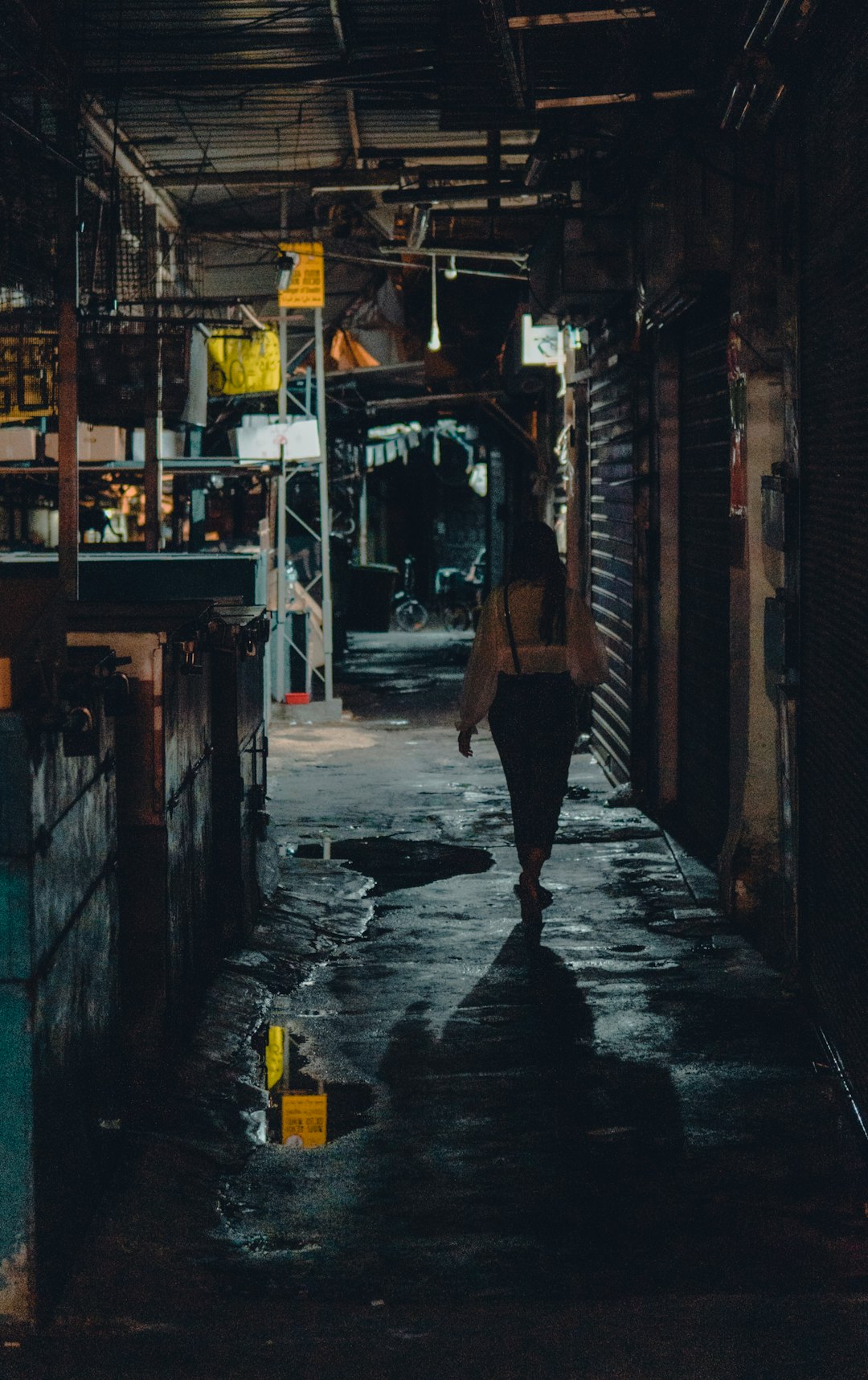 woman in black tank top and black skirt walking on sidewalk during night time