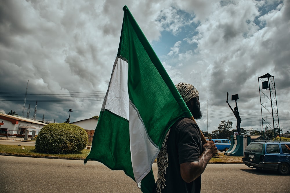 woman in black and white hijab holding green flag