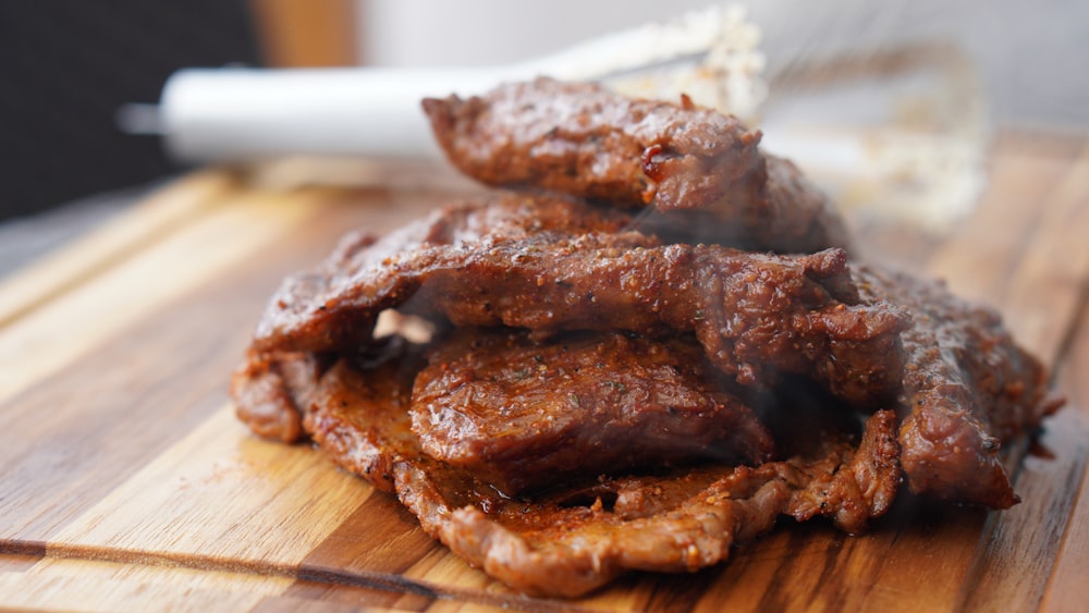 carne grelhada na tábua de cortar madeira marrom