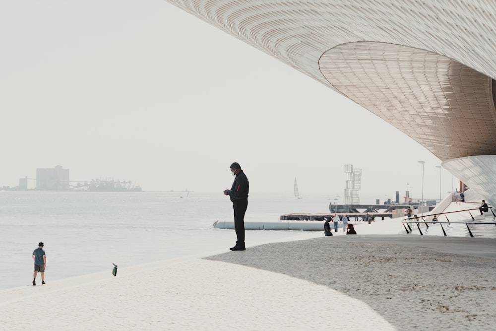 man in black jacket standing on beach during daytime