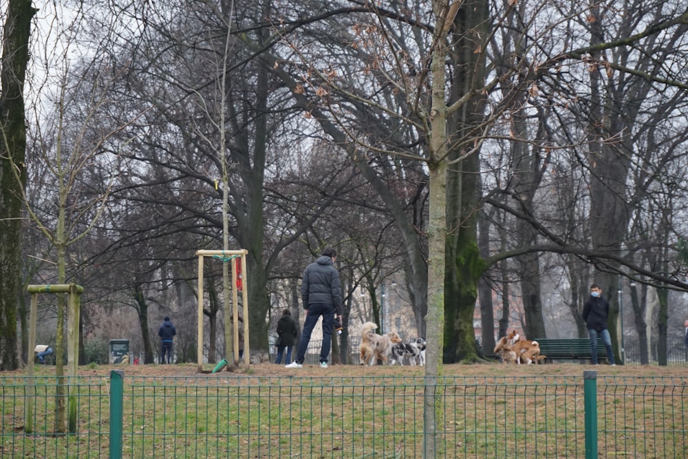 man in black jacket standing beside brown dog