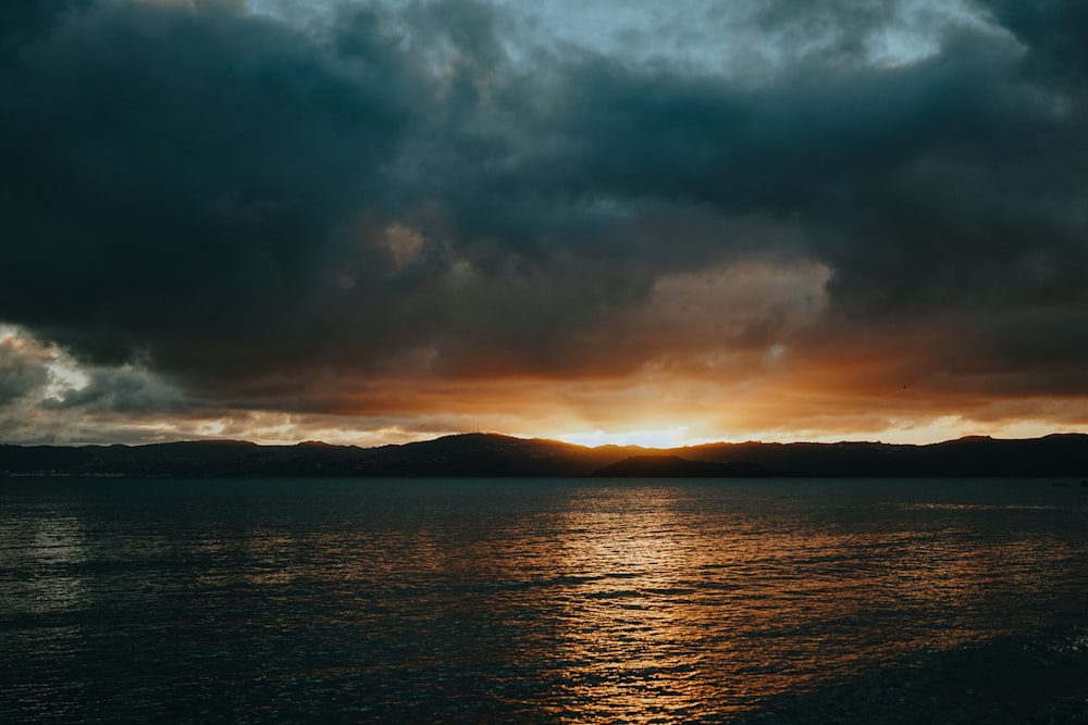 body of water under cloudy sky during sunset