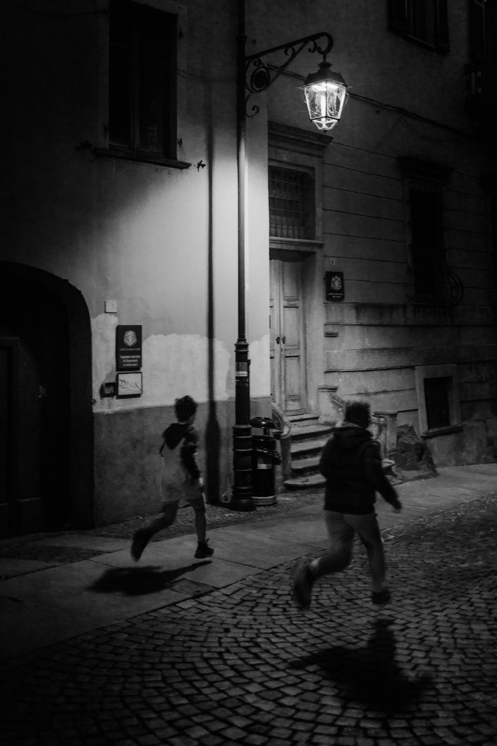 grayscale photo of man and woman walking on hallway