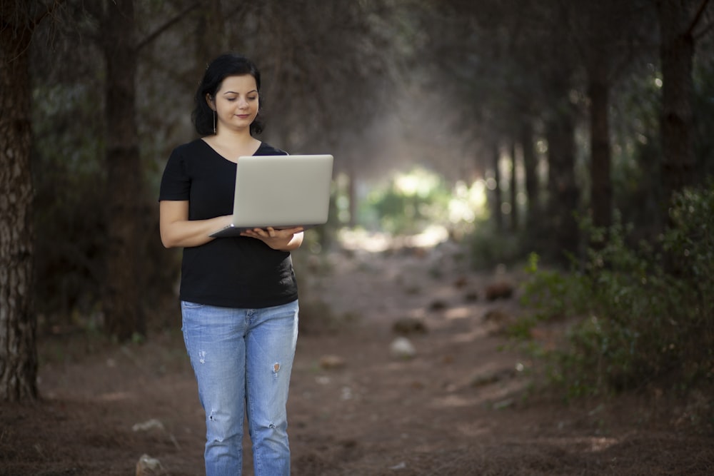 woman in black t-shirt and blue denim jeans holding white box