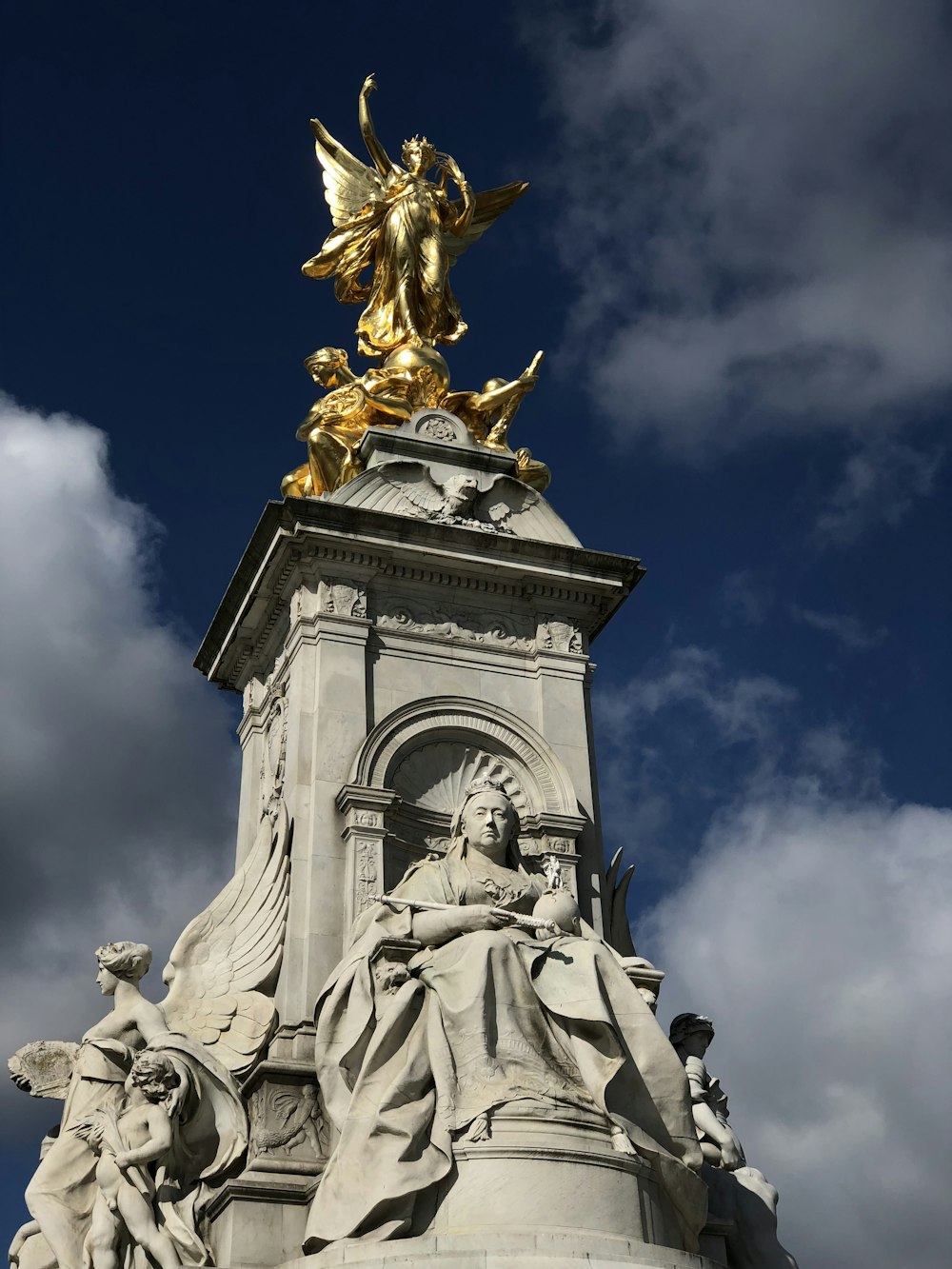 statua d'oro sotto il cielo nuvoloso durante il giorno