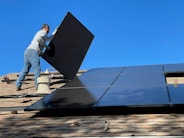 man in white dress shirt and blue denim jeans sitting on white and black solar panel