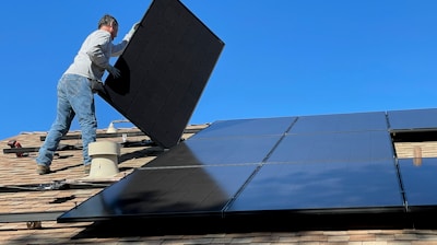 man in white dress shirt and blue denim jeans sitting on white and black solar panel