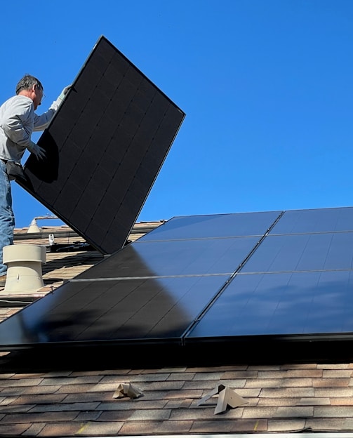 man in white dress shirt and blue denim jeans sitting on white and black solar panel