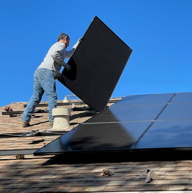 man in white dress shirt and blue denim jeans sitting on white and black solar panel