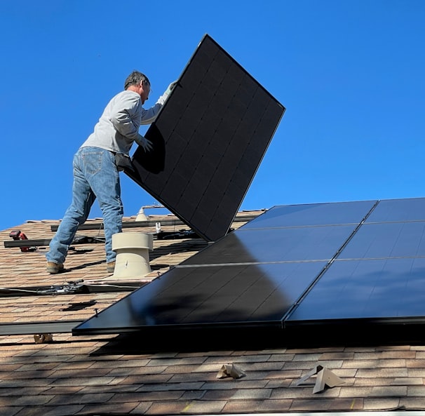 man in white dress shirt and blue denim jeans sitting on white and black solar panel