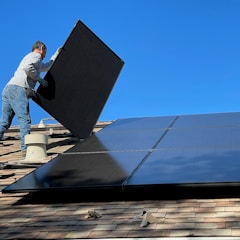 man in white dress shirt and blue denim jeans sitting on white and black solar panel