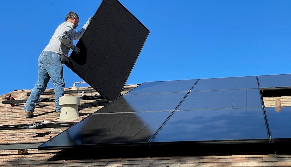 man in white dress shirt and blue denim jeans sitting on white and black solar panel