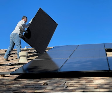 man in white dress shirt and blue denim jeans sitting on white and black solar panel