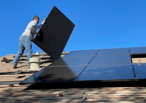 man in white dress shirt and blue denim jeans sitting on white and black solar panel