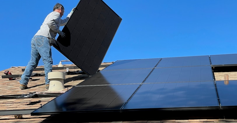 man in white dress shirt and blue denim jeans sitting on white and black solar panel