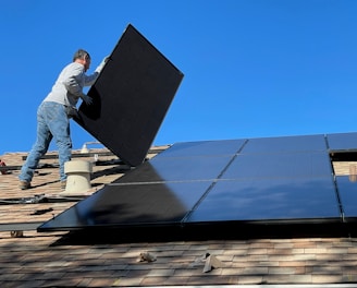 man in white dress shirt and blue denim jeans sitting on white and black solar panel