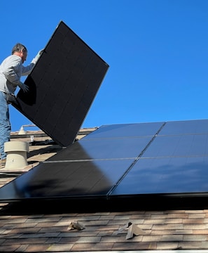 man in white dress shirt and blue denim jeans sitting on white and black solar panel