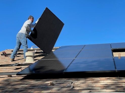 man in white dress shirt and blue denim jeans sitting on white and black solar panel